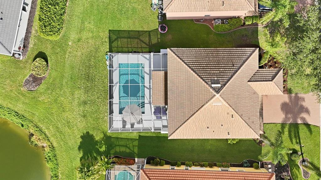 An aerial view shows a house with a screened-in pool and a tiled roof — 6904 74TH STREET CIRCLE E, BRADENTON, FL