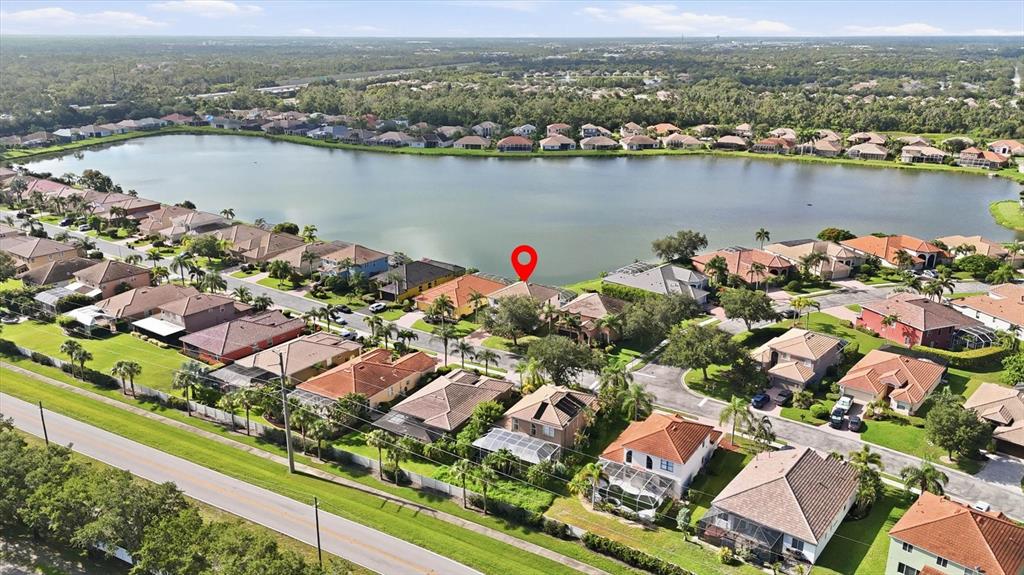 An aerial view shows a suburban neighborhood with houses surrounding a large lake — 6904 74TH STREET CIRCLE E, BRADENTON, FL