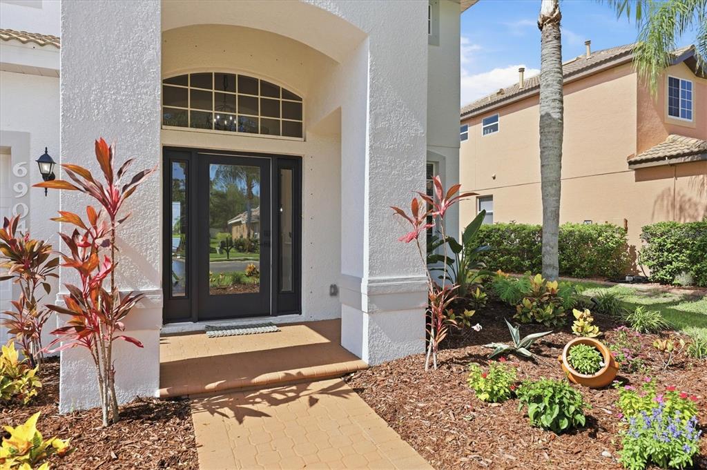 The front entrance of a white house features a dark door with glass side panels — 6904 74TH STREET CIRCLE E, BRADENTON, FL