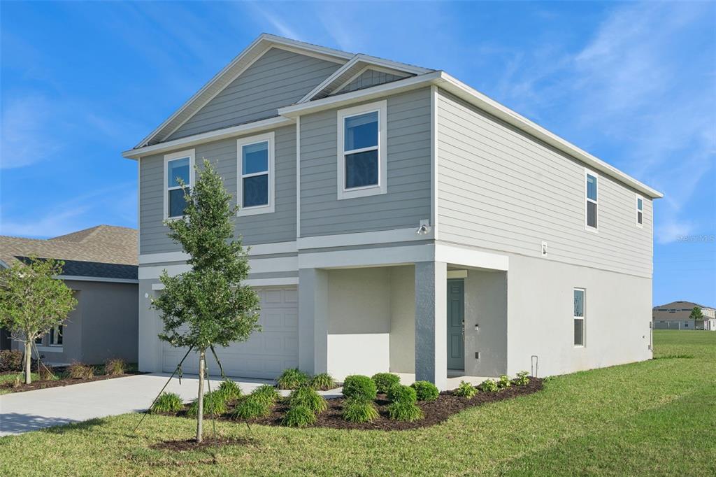 A two-story house with gray horizontal siding, a white stucco base, and a front garage — 4904 BLUEBELL COURT, HAINES CITY, FL
