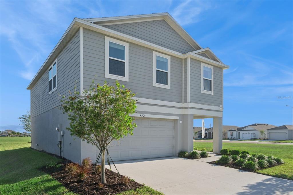 A two-story house with gray horizontal siding and a two-car garage under a blue sky — 4904 BLUEBELL COURT, HAINES CITY, FL