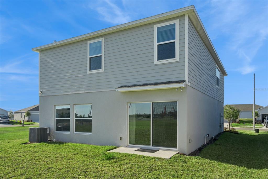 The rear exterior of a two-story house features gray siding, stucco walls, and sliding doors — 4904 BLUEBELL COURT, HAINES CITY, FL