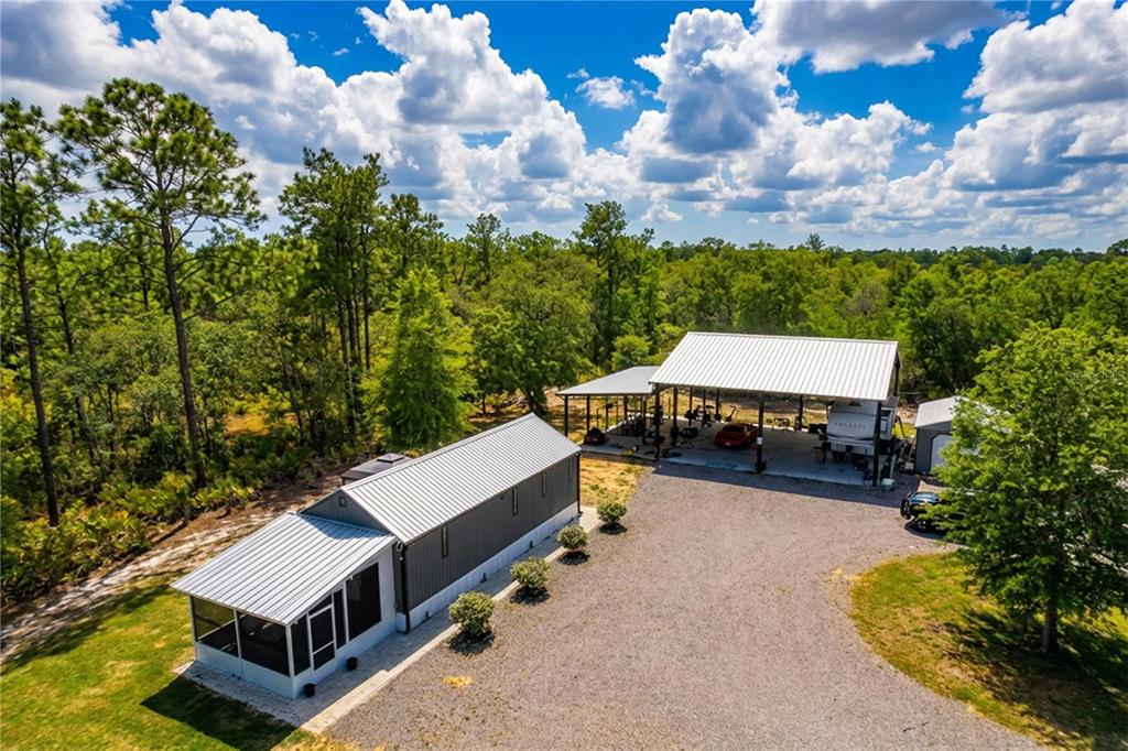 An aerial view shows a metal-roofed house with a screened porch and a large carport — 10388 S SUNCOAST BOULEVARD, HOMOSASSA, FL
