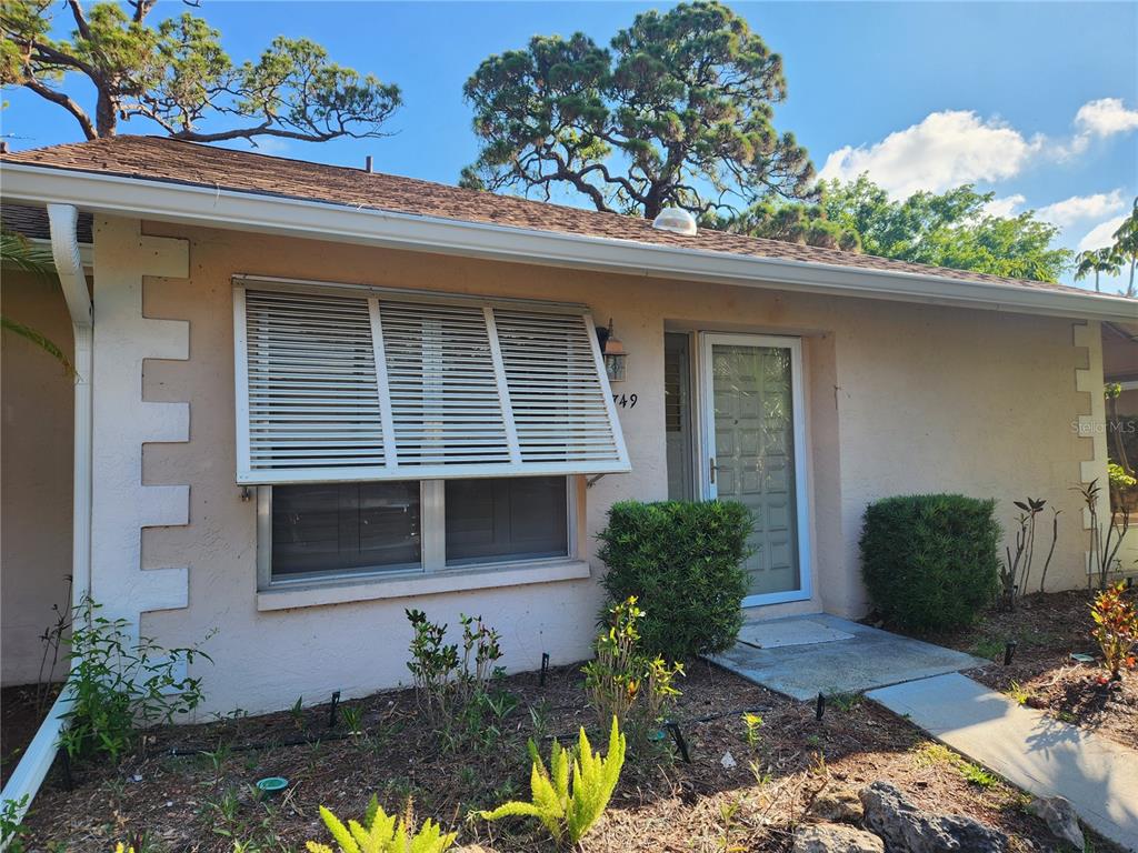 A single-story house exterior features a beige stucco facade, white shutters, and a front door — 749 N JEFFERSON AVENUE UNIT 749, SARASOTA, FL