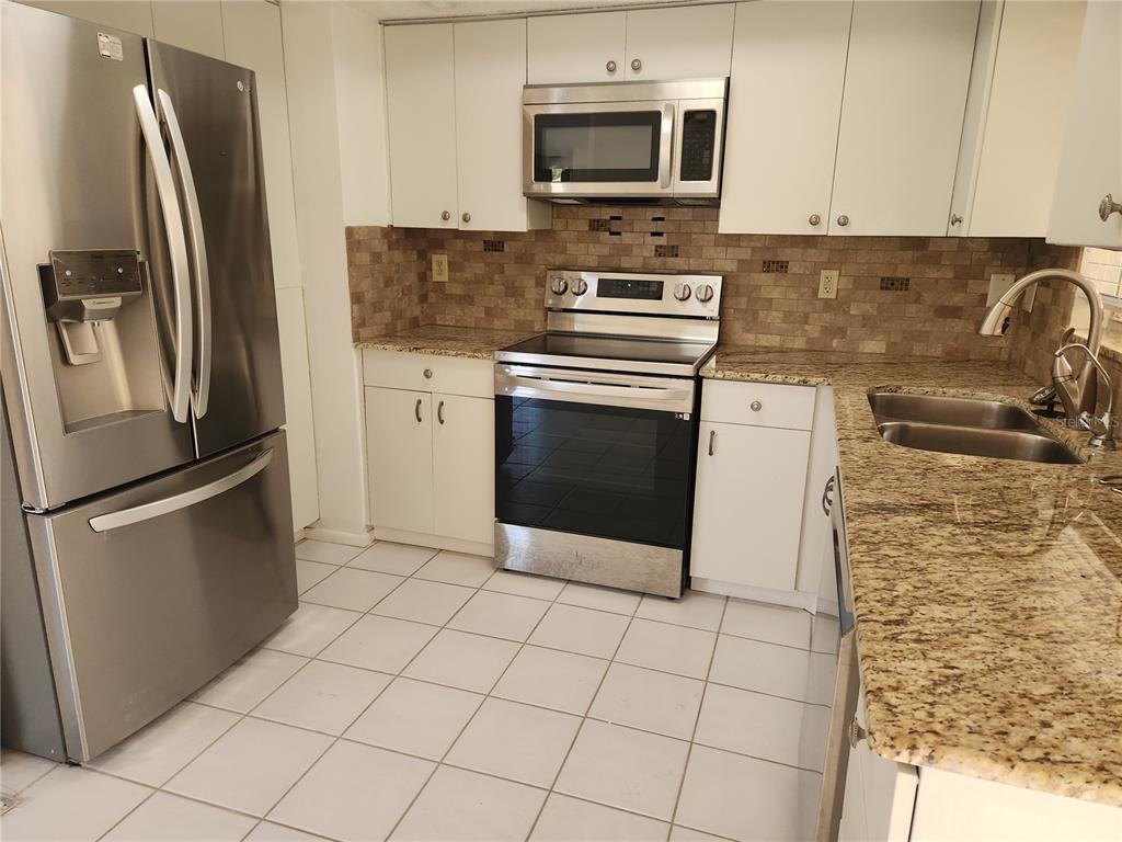 A kitchen featuring white cabinets, stainless steel appliances, granite countertops, and a tiled floor — 749 N JEFFERSON AVENUE UNIT 749, SARASOTA, FL
