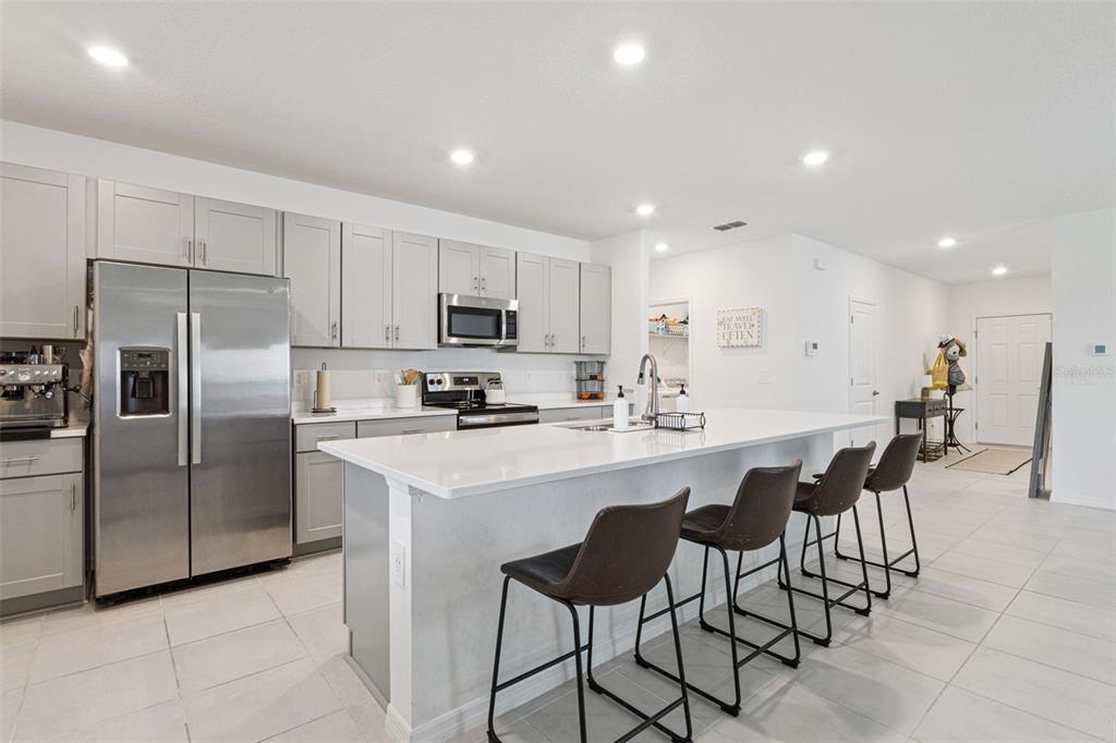 A modern kitchen features gray cabinetry, stainless steel appliances, and a large white island — 1099 CALICO POINTE CIRCLE, GROVELAND, FL