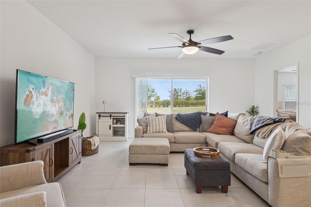 A living room features a sectional sofa, a television on a wooden console, and tile flooring — 1099 CALICO POINTE CIRCLE, GROVELAND, FL