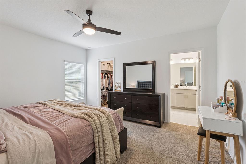 A bedroom features a bed, a dark wood dresser with a mirror, and a vanity — 1099 CALICO POINTE CIRCLE, GROVELAND, FL