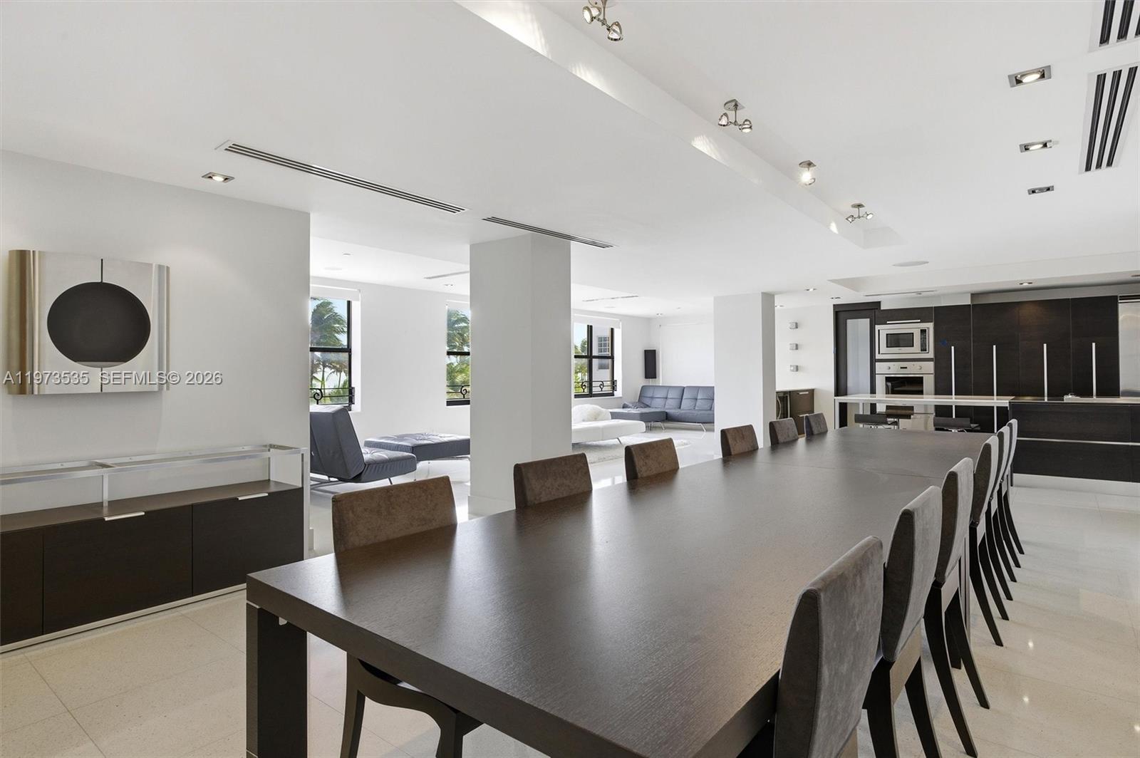 A long dark dining table sits in a modern open-plan room with white walls — 1330 Ocean Dr, Miami Beach FL 33139, MIAMI BEACH, FL