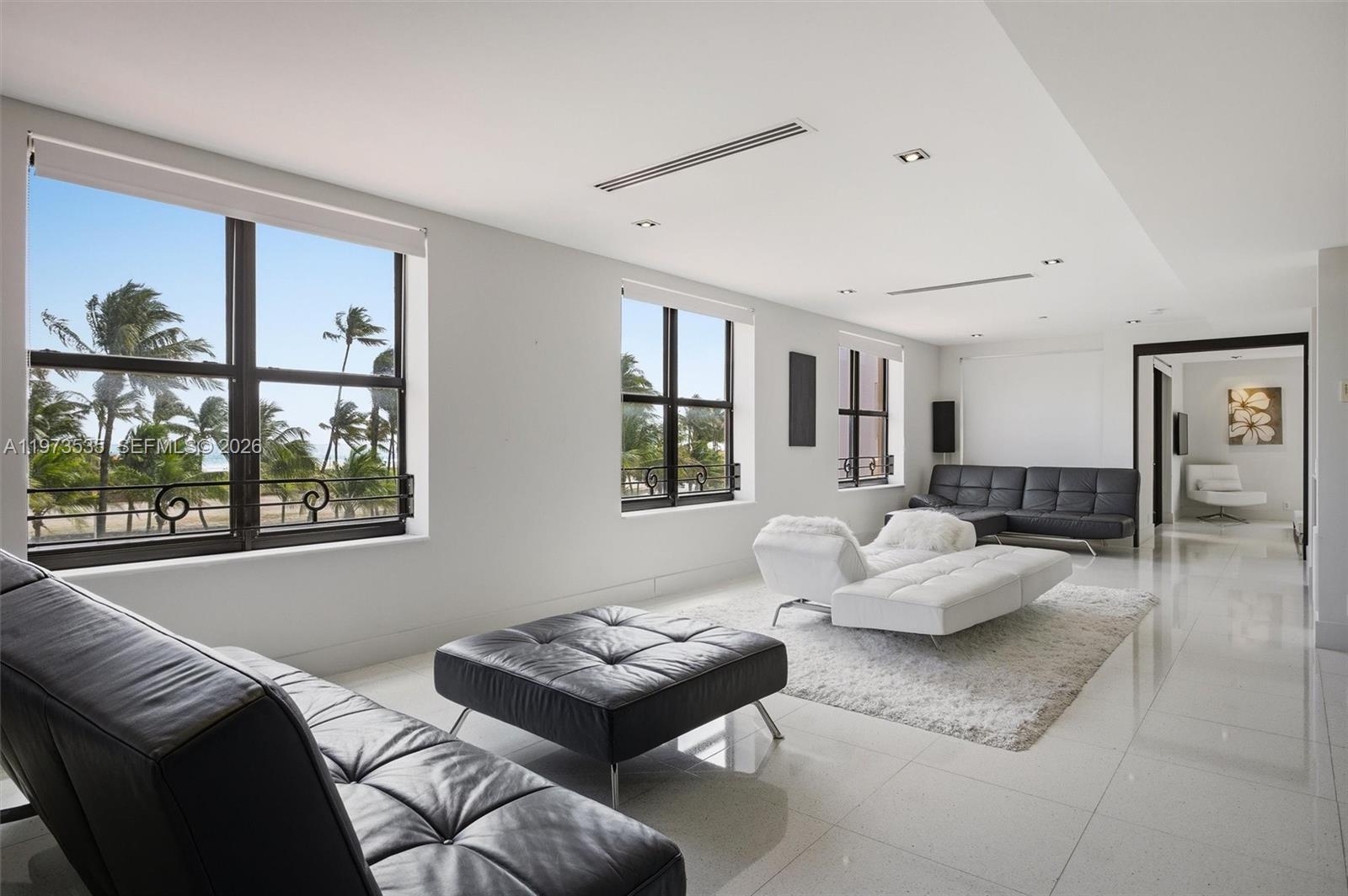 A modern living room features white tile floors, black leather furniture, and large windows — 1330 Ocean Dr, Miami Beach FL 33139, MIAMI BEACH, FL