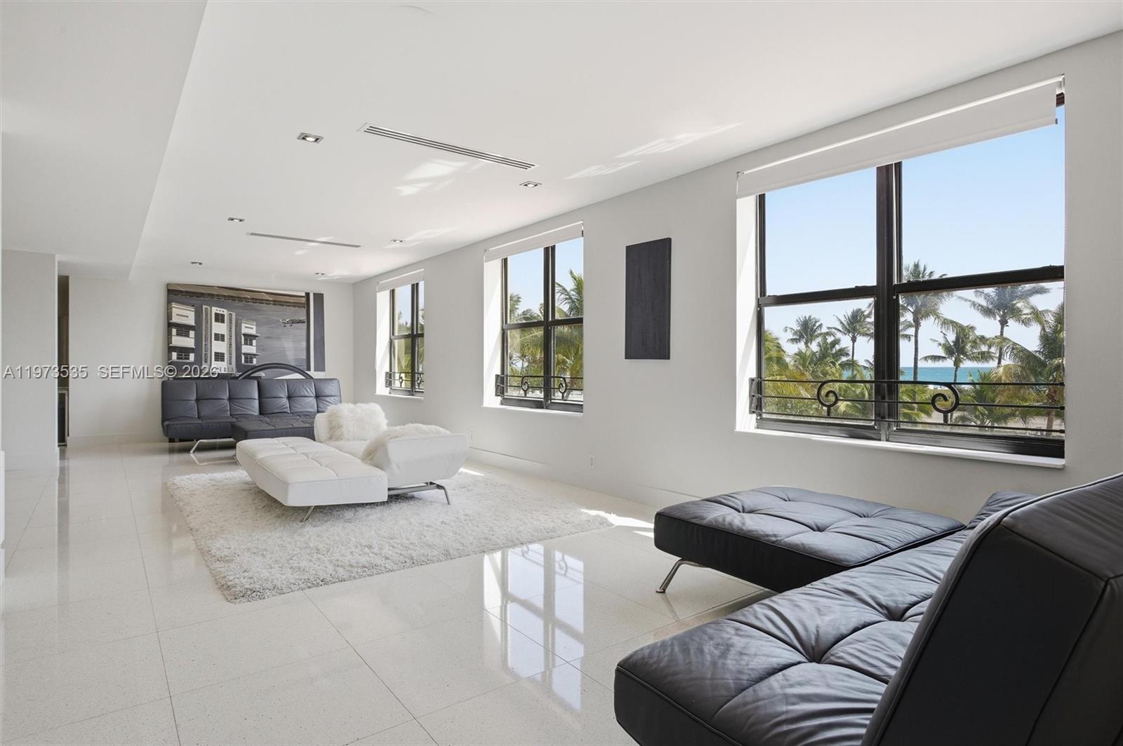 A bright living room features white tile floors, two black leather sofas, and ocean views — 1330 Ocean Dr, Miami Beach FL 33139, MIAMI BEACH, FL