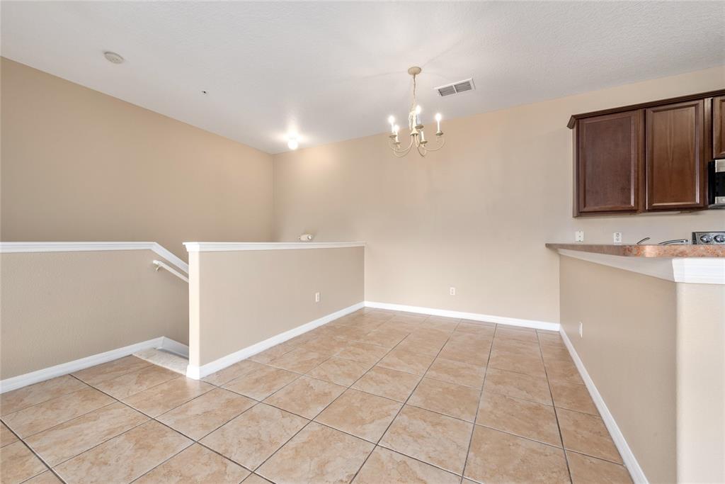 A dining area features tan walls, tile flooring, a chandelier, and a kitchen breakfast bar — 7531 PELLHAM WAY UNIT 77, KISSIMMEE, FL