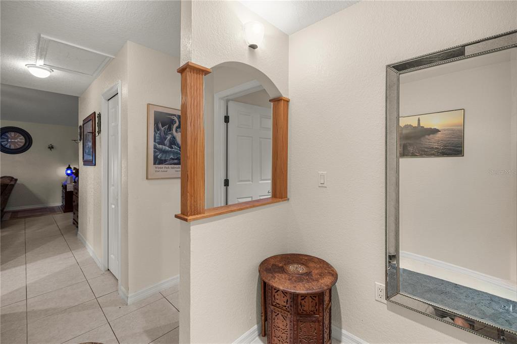 A hallway features tiled floors, a decorative arched cutout with wooden pillars, and a large mirror — 2635 NE 7TH STREET UNIT 102, OCALA, FL