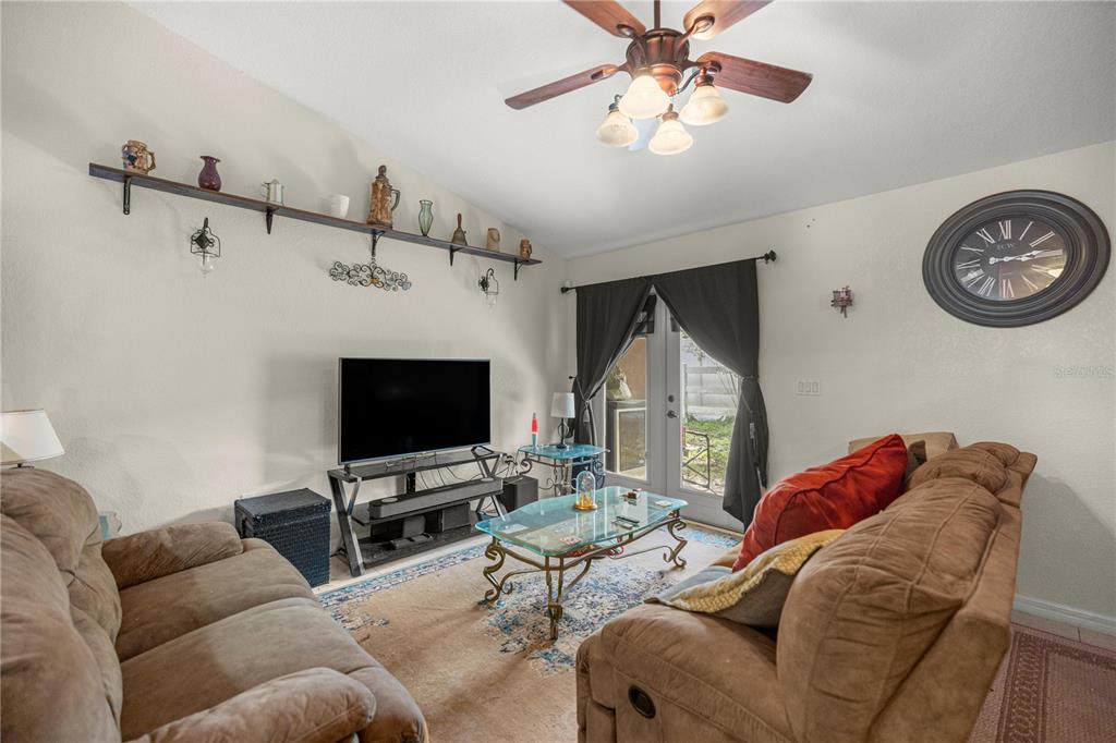 A living room features two brown sofas, a glass coffee table, and a wall-mounted shelf — 2635 NE 7TH STREET UNIT 102, OCALA, FL