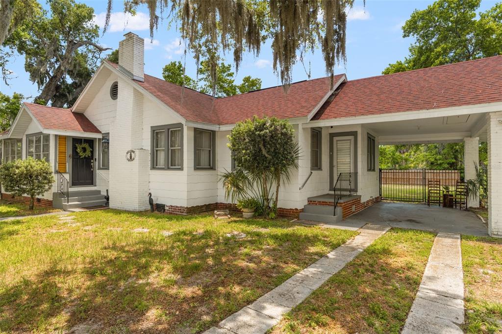 A white house with a red roof, a brick chimney, and an attached carport — 5845 GRAND BOULEVARD, NEW PORT RICHEY, FL