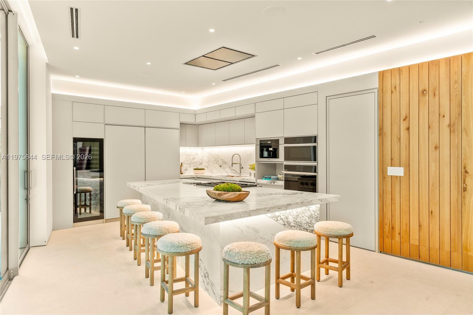 A modern kitchen features a marble island with bar stools and integrated lighting — 1616 Onaway Dr, Miami FL 33133, MIAMI, FL