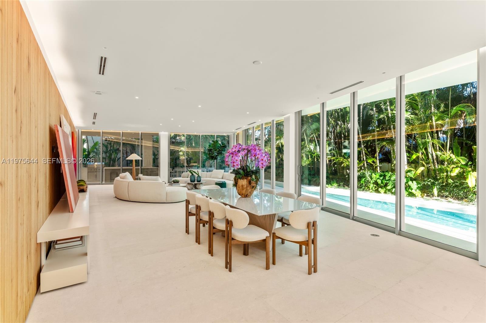 A modern dining and living area features floor-to-ceiling windows overlooking a swimming pool — 1616 Onaway Dr, Miami FL 33133, MIAMI, FL