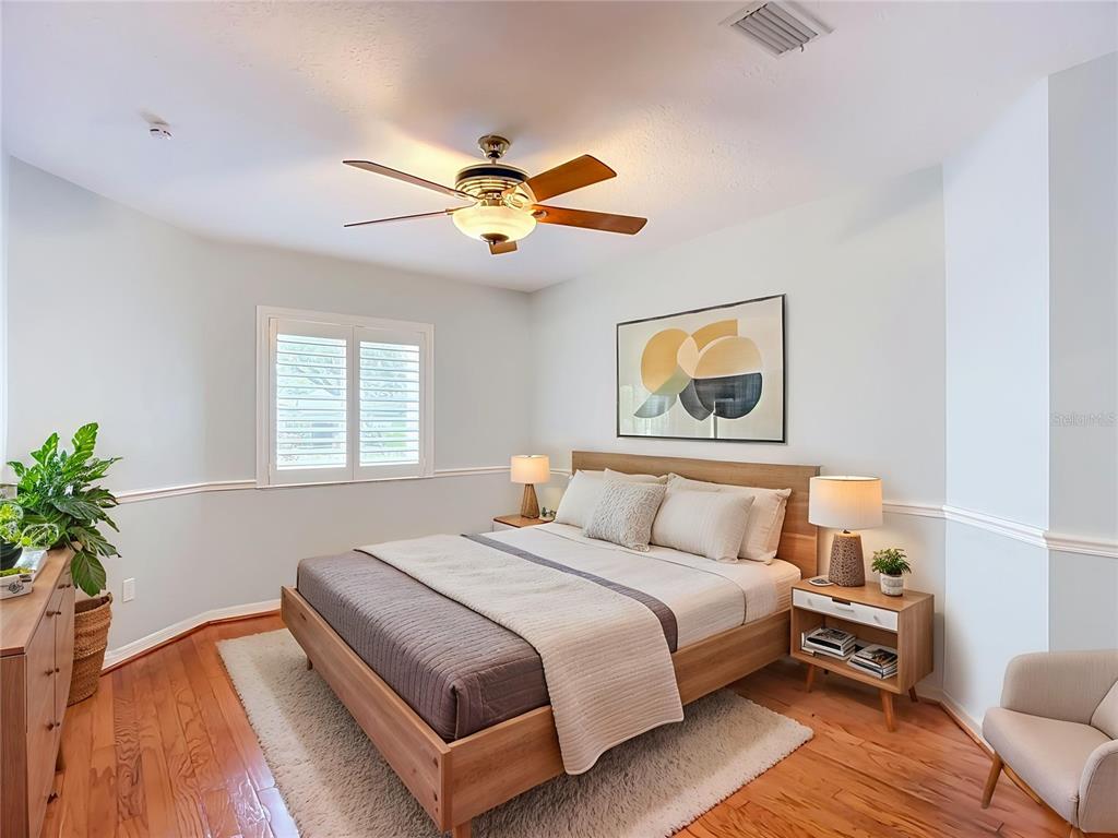 A bedroom features a wooden bed frame, a ceiling fan, and hardwood floors — 15886 SANCTUARY DRIVE, TAMPA, FL