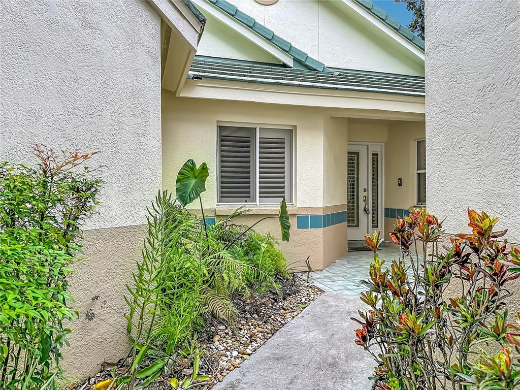 An exterior view shows a house entrance with a walkway, landscaping, and a tiled roof — 15886 SANCTUARY DRIVE, TAMPA, FL