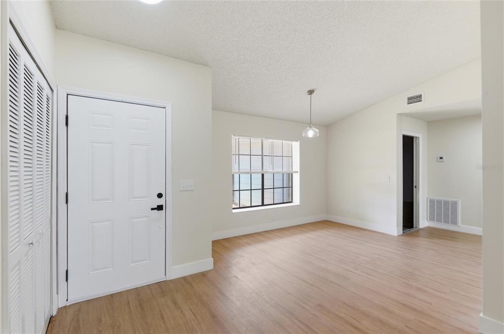 An interior view of a room with light wood flooring, white walls, and a white door — 1591 MALALUKA STREET, DELTONA, FL