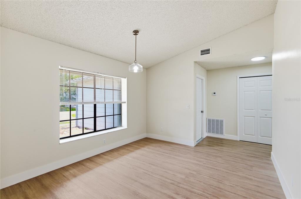 An empty dining area features light wood-look flooring, a single pendant light, and a window — 1591 MALALUKA STREET, DELTONA, FL