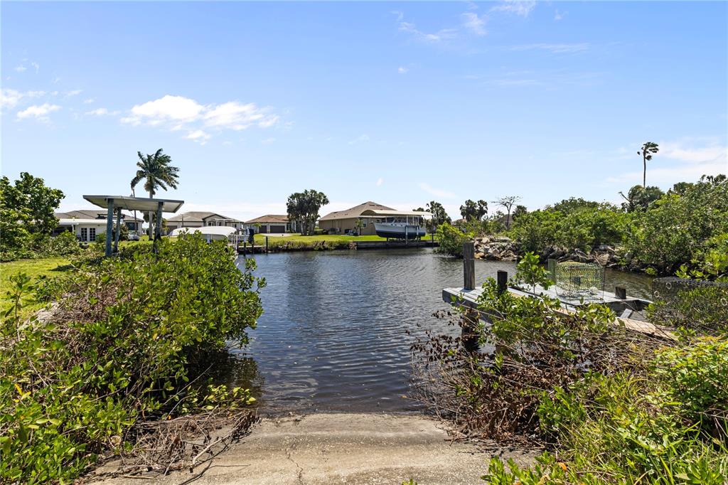 A concrete boat ramp leads into a canal with a dock and residential homes — 4020 PALM DRIVE, PUNTA GORDA, FL