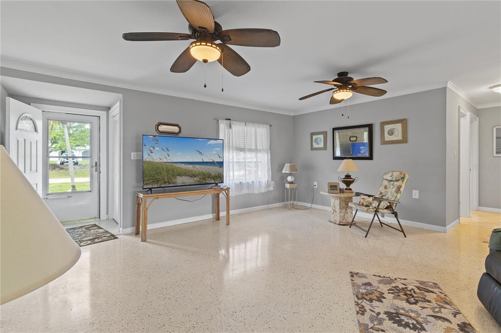 A living room with gray walls, a ceiling fan, a television, and light-colored terrazzo flooring — 4020 PALM DRIVE, PUNTA GORDA, FL