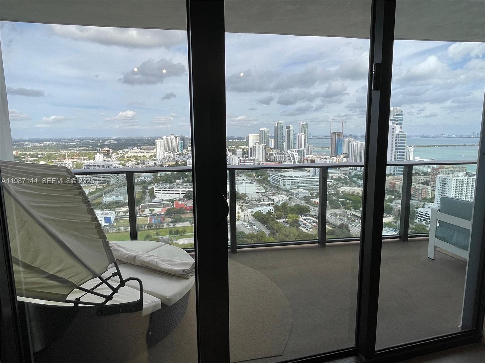 A balcony with outdoor furniture overlooks a city skyline and a body of water — 1600 NE 1st Ave # 3717, Miami FL 33132, MIAMI, FL
