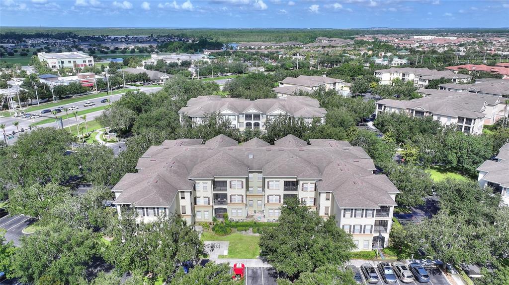An aerial view shows a multi-story apartment building surrounded by trees and parking lots — 11564 MIZZON DRIVE UNIT 923, WINDERMERE, FL