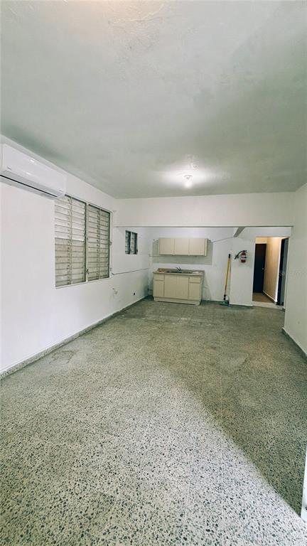An open-concept room features a small kitchenette, terrazzo flooring, and a wall-mounted air conditioner — 36 Calle Julian Blanco So BO PUEBLO, VEGA BAJA, PR