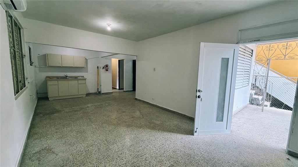 An open-plan living area features a small kitchen, terrazzo flooring, and a white door — 36 Calle Julian Blanco So BO PUEBLO, VEGA BAJA, PR