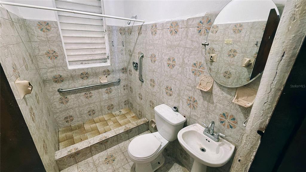 A small bathroom features tiled walls, a walk-in shower area, a toilet, and a pedestal sink — 36 Calle Julian Blanco So BO PUEBLO, VEGA BAJA, PR