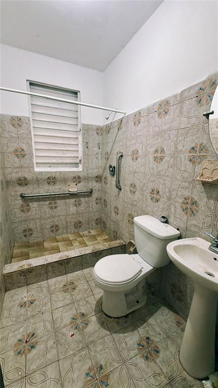 A bathroom features a tiled shower stall with grab bars, a toilet, and a pedestal sink — 36 Calle Julian Blanco So BO PUEBLO, VEGA BAJA, PR