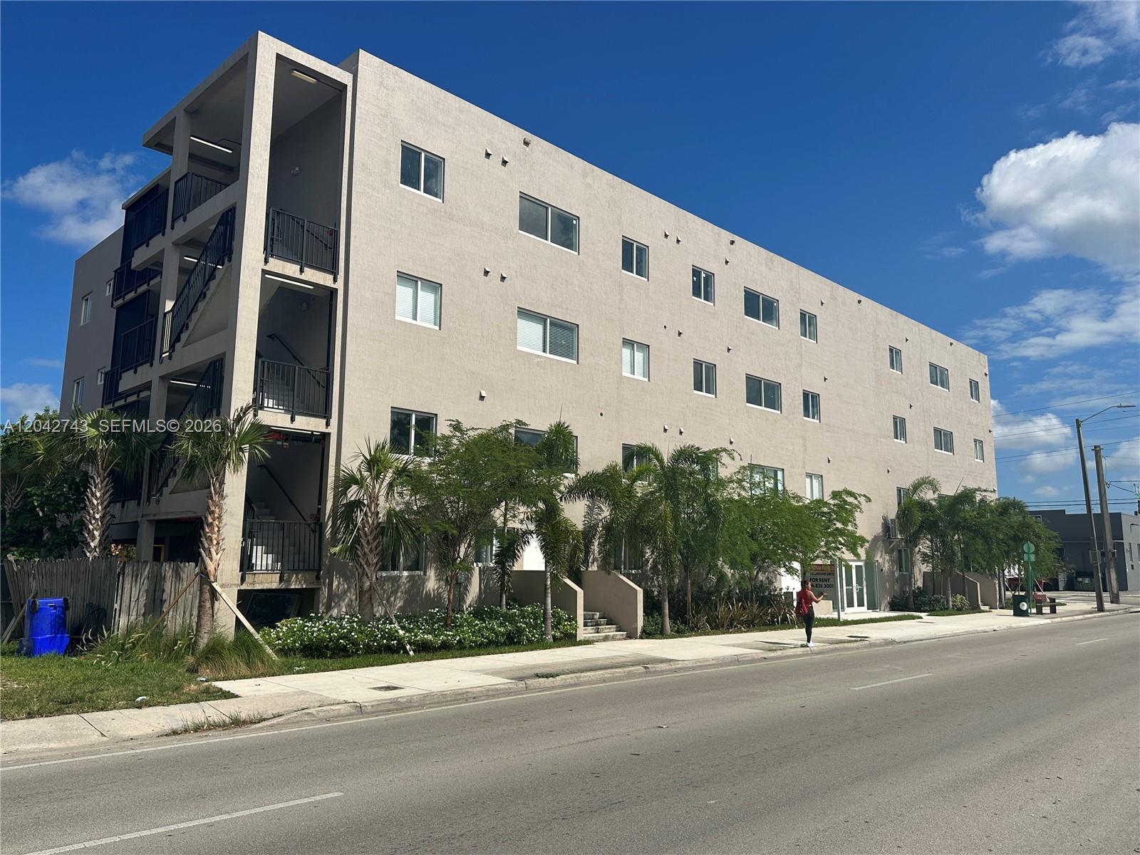 A four-story beige apartment building with exterior staircases stands along a paved street — 2311 NW 22nd Ave, Miami FL 33142, MIAMI, FL