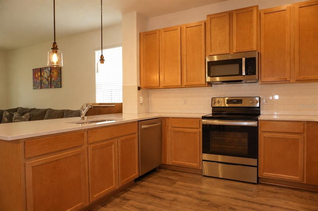 A kitchen features light wood cabinets, stainless steel appliances, and white subway tile backsplashes — 4909 OLIVIA COURT, ST CLOUD, FL