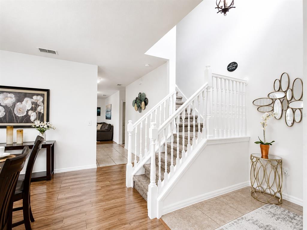 An entryway features a staircase with white railings, wood flooring, and a tiled landing area — 1056 CYPRESS POINTE BOULEVARD, DAVENPORT, FL