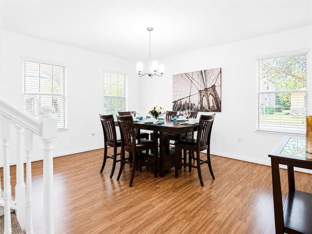 A dining room features a dark wood table, six chairs, and light wood flooring — 1056 CYPRESS POINTE BOULEVARD, DAVENPORT, FL