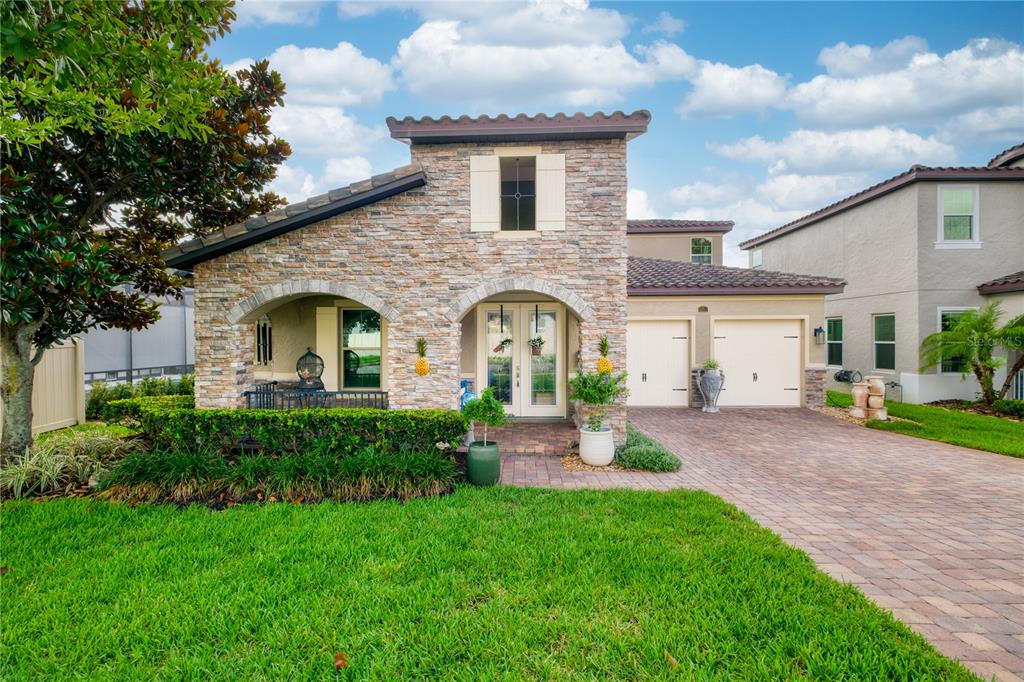 A stone-faced house with a paved driveway, arched entryway, and a green lawn — 1651 AMSEL FALLS PARK TERRACE, WINTER GARDEN, FL