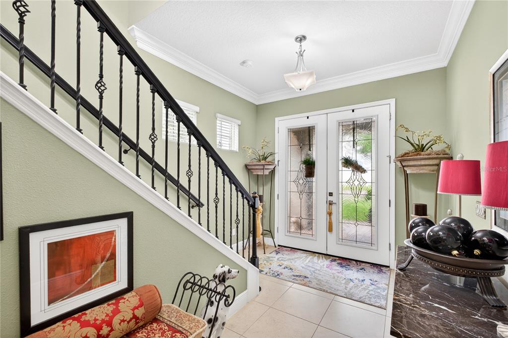 A bright entryway features a staircase with black iron railings, tile flooring, and double doors — 1651 AMSEL FALLS PARK TERRACE, WINTER GARDEN, FL