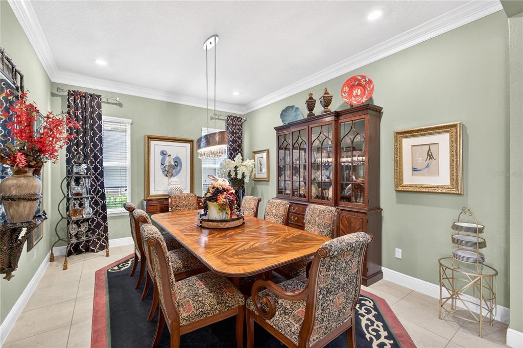 A formal dining room features a wooden table, patterned chairs, a china cabinet, and sage walls — 1651 AMSEL FALLS PARK TERRACE, WINTER GARDEN, FL