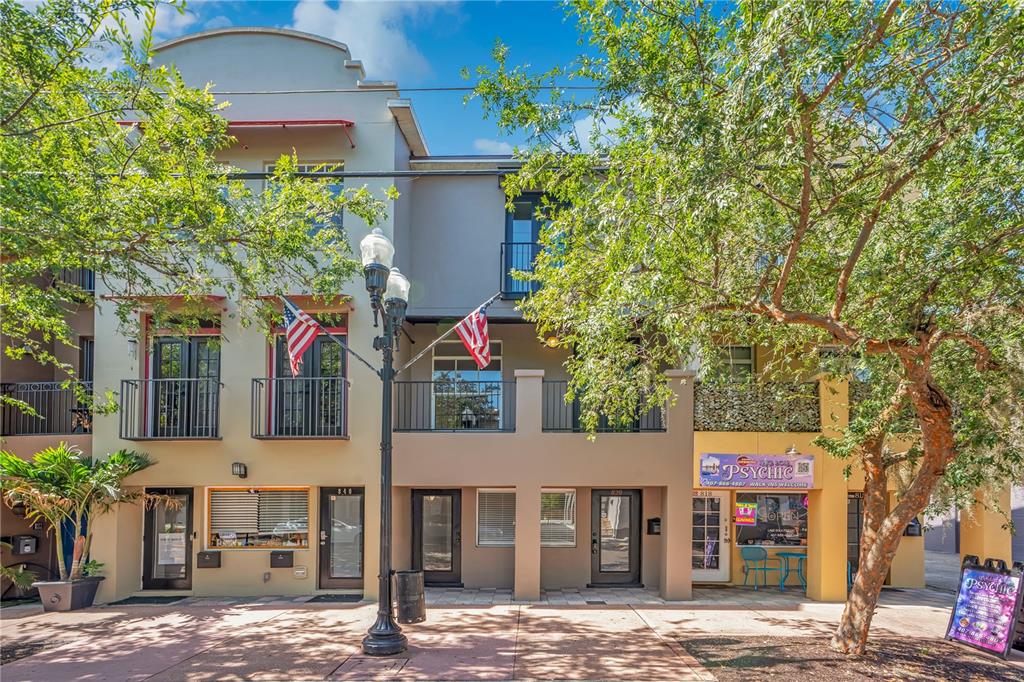 A three-story commercial building with balconies, American flags, and a ground-level psychic shop — 828 E WASHINGTON STREET, ORLANDO, FL