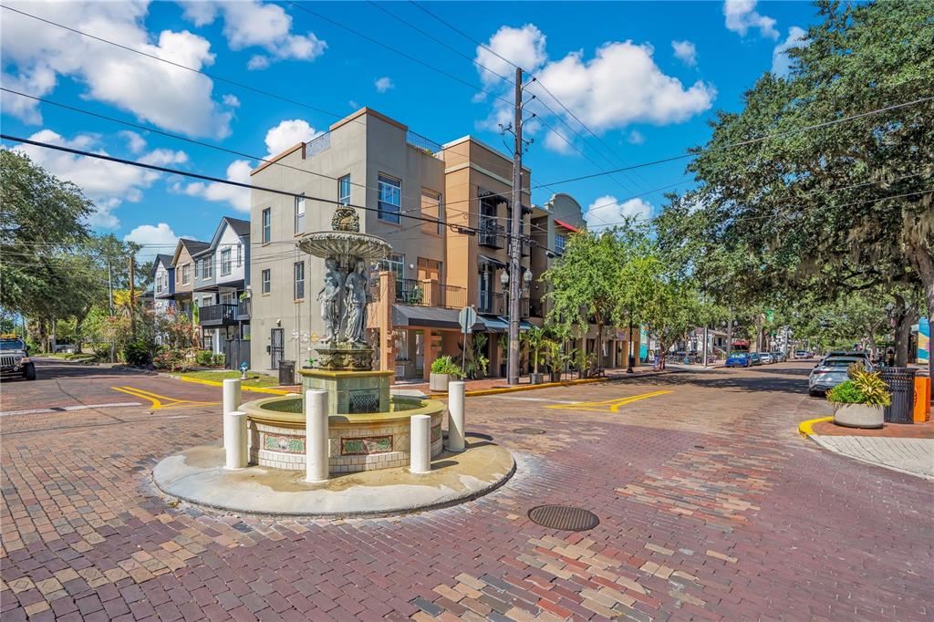 A decorative stone fountain stands in the center of a brick-paved street intersection — 828 E WASHINGTON STREET, ORLANDO, FL