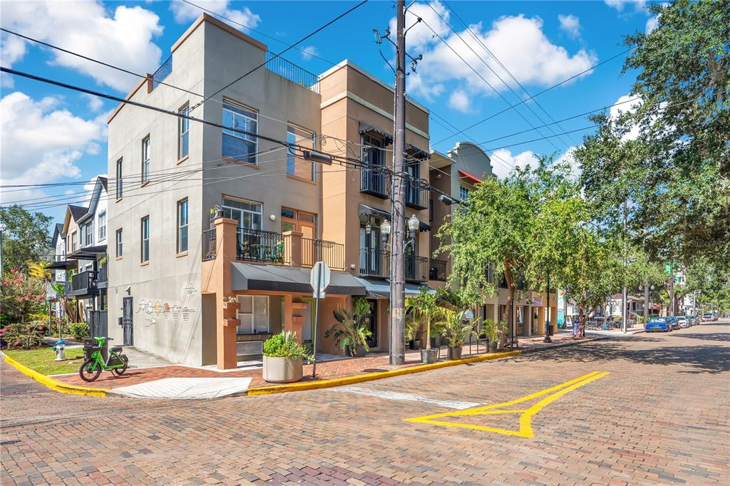 A three-story building with a brick-paved street corner and a green rental scooter — 828 E WASHINGTON STREET, ORLANDO, FL