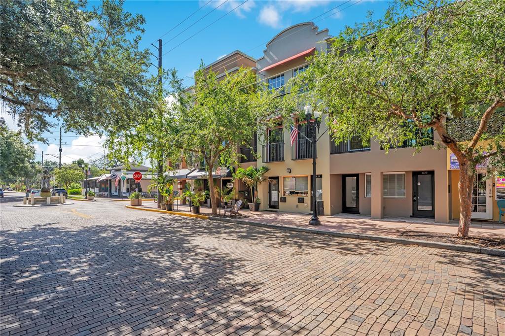 A brick street leads to a row of multi-story buildings with balconies and storefronts — 828 E WASHINGTON STREET, ORLANDO, FL