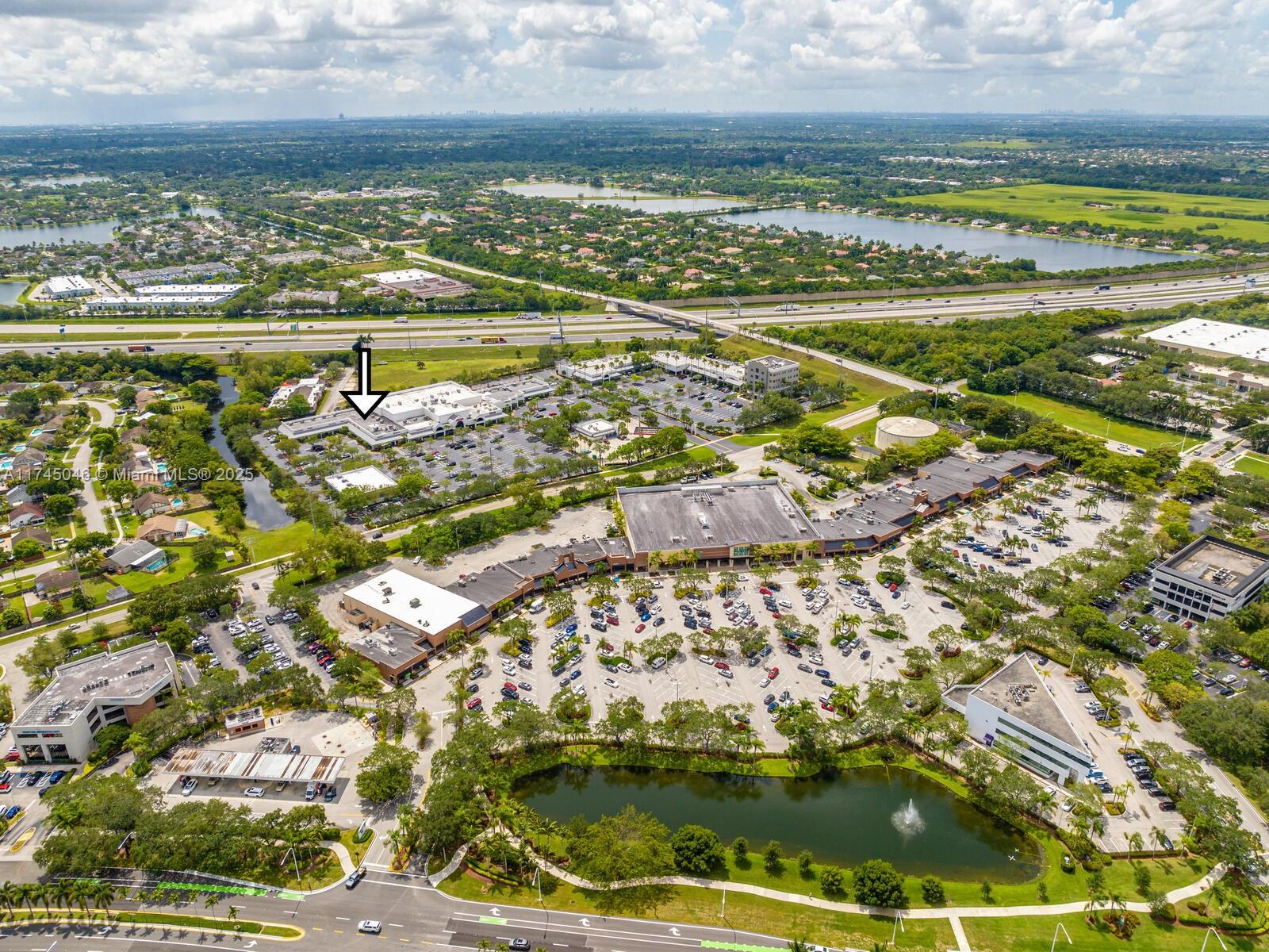 This aerial view shows a commercial shopping center with parking lots and a central pond — 1320 SW 160th Ave, Weston FL 33326, WESTON, FL