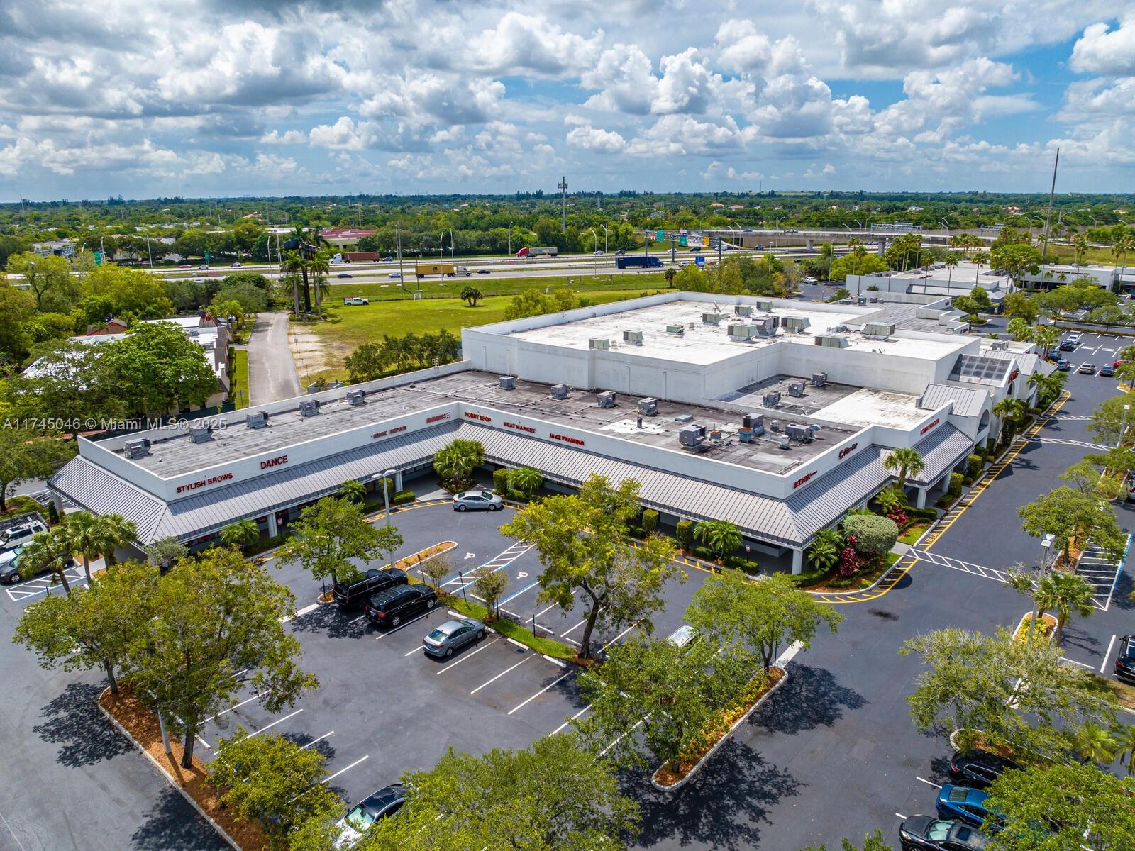 An aerial view shows a commercial strip mall with a parking lot and surrounding greenery — 1320 SW 160th Ave, Weston FL 33326, WESTON, FL