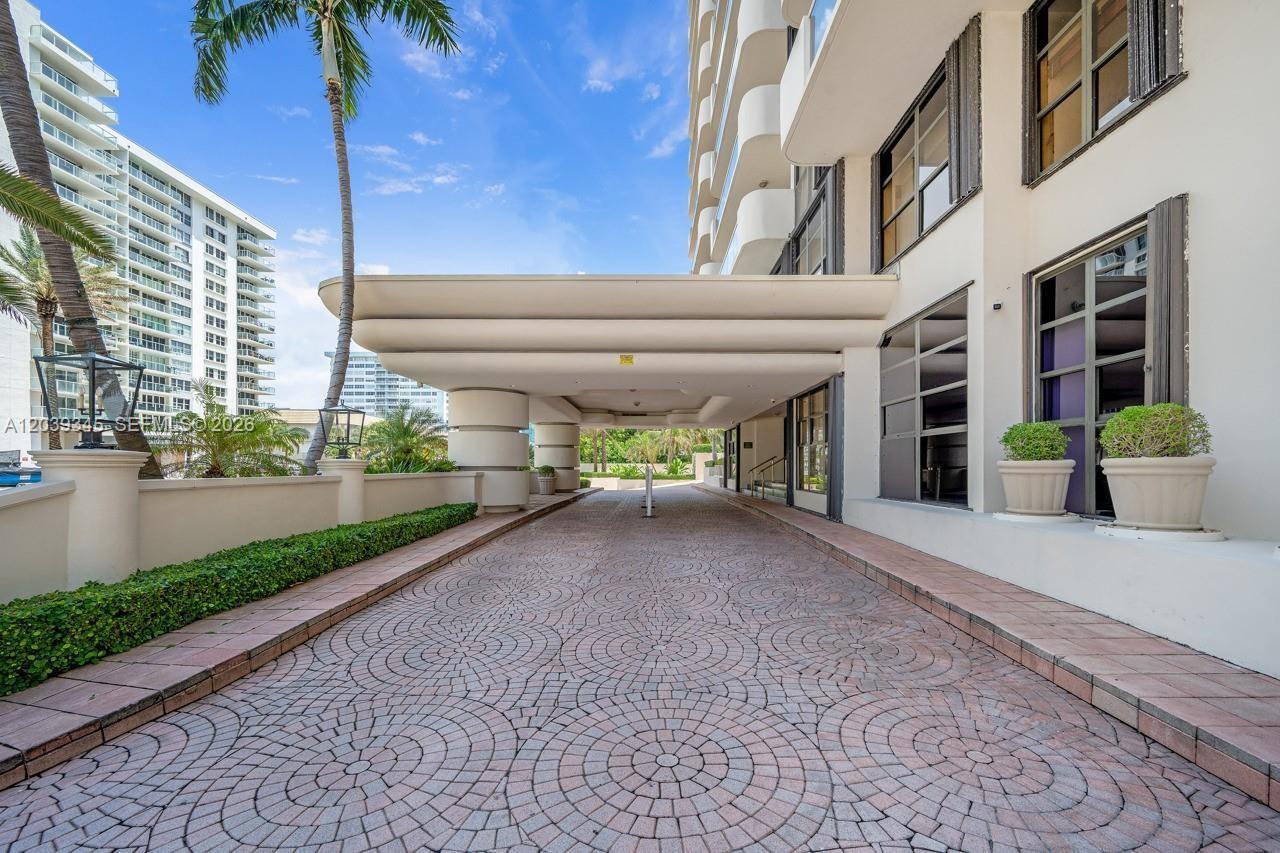 A paved driveway leads to the covered entrance of a multi-story residential building — 5757 Collins Ave # 702, Miami Beach FL 33140, MIAMI BEACH, FL