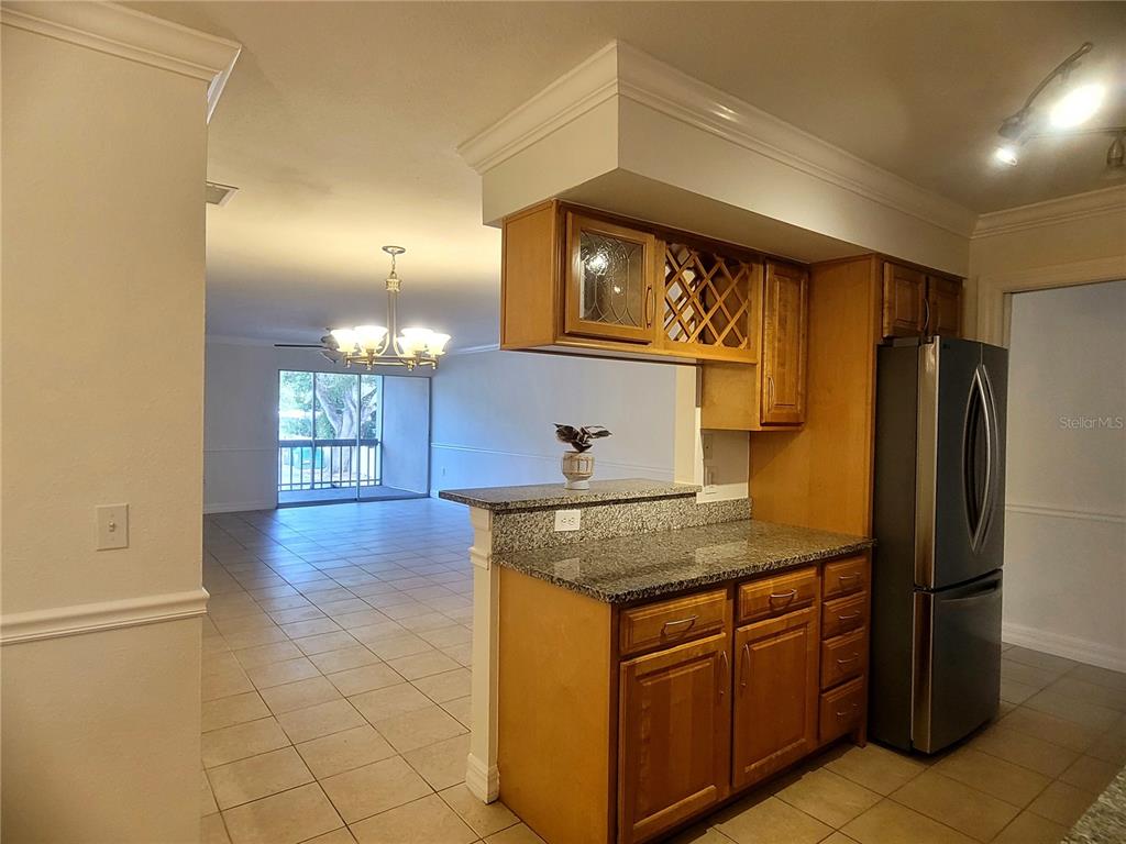 A kitchen with wood cabinets and granite countertops overlooks an open living area — 3360 S OSPREY AVENUE UNIT 201B, SARASOTA, FL