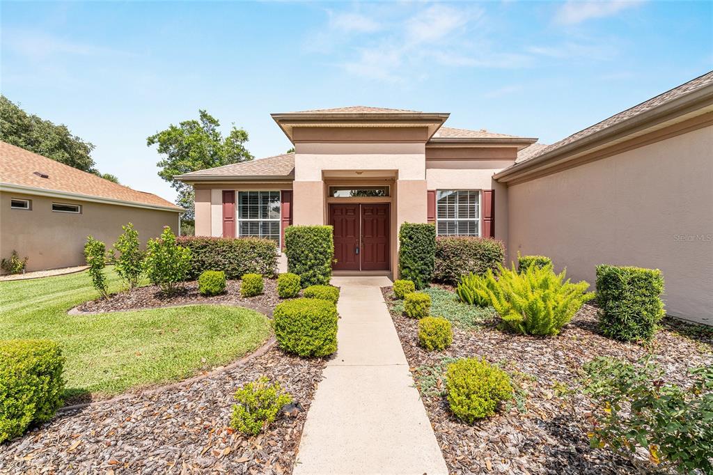 The front exterior of a single-story house features a concrete walkway leading to the entrance — 12947 SE 97TH TERRACE ROAD, SUMMERFIELD, FL