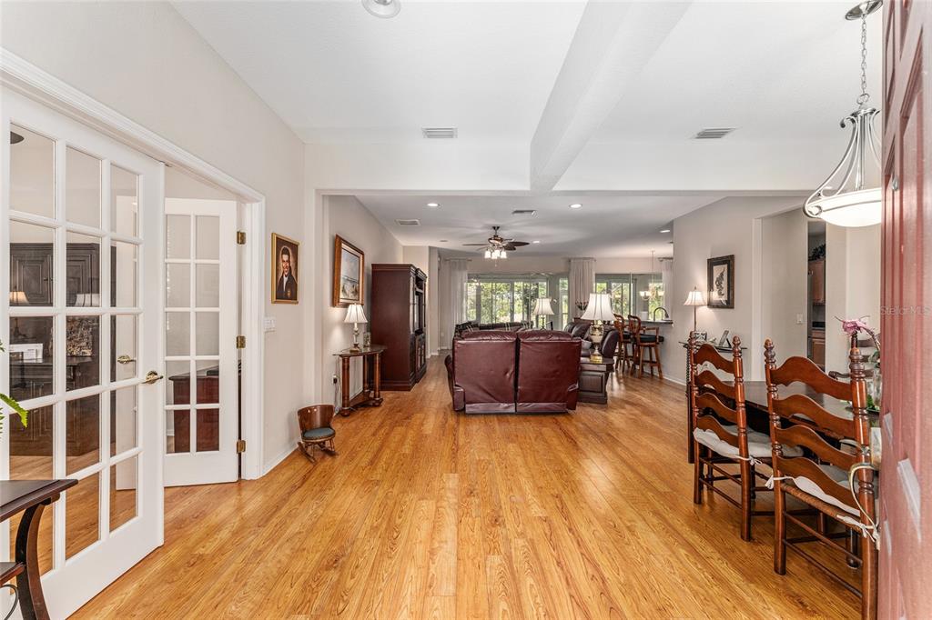 An open-concept living and dining area features hardwood floors, a ceiling fan, and French doors — 12947 SE 97TH TERRACE ROAD, SUMMERFIELD, FL